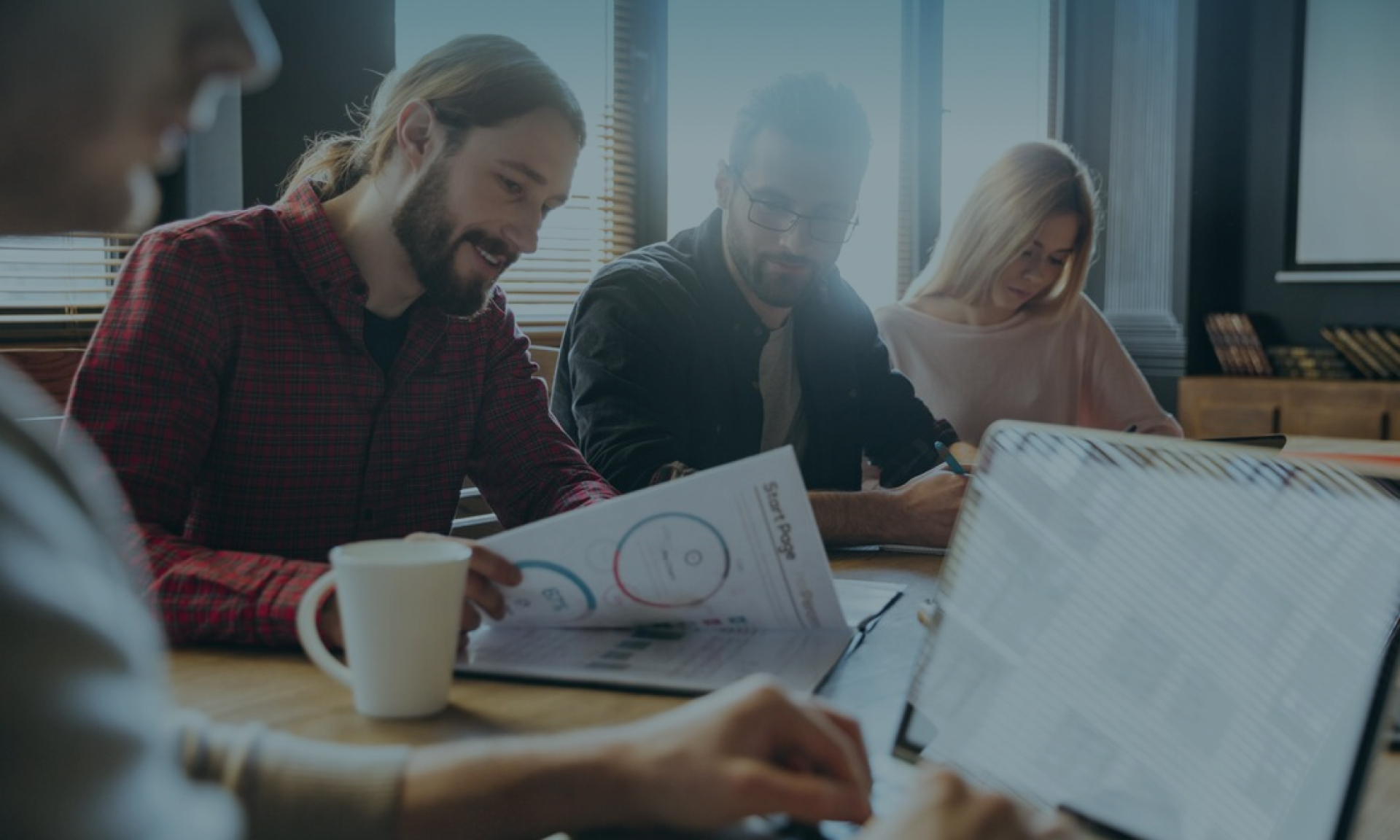 Business team meeting: Diverse group reviews charts and data at office conference table.