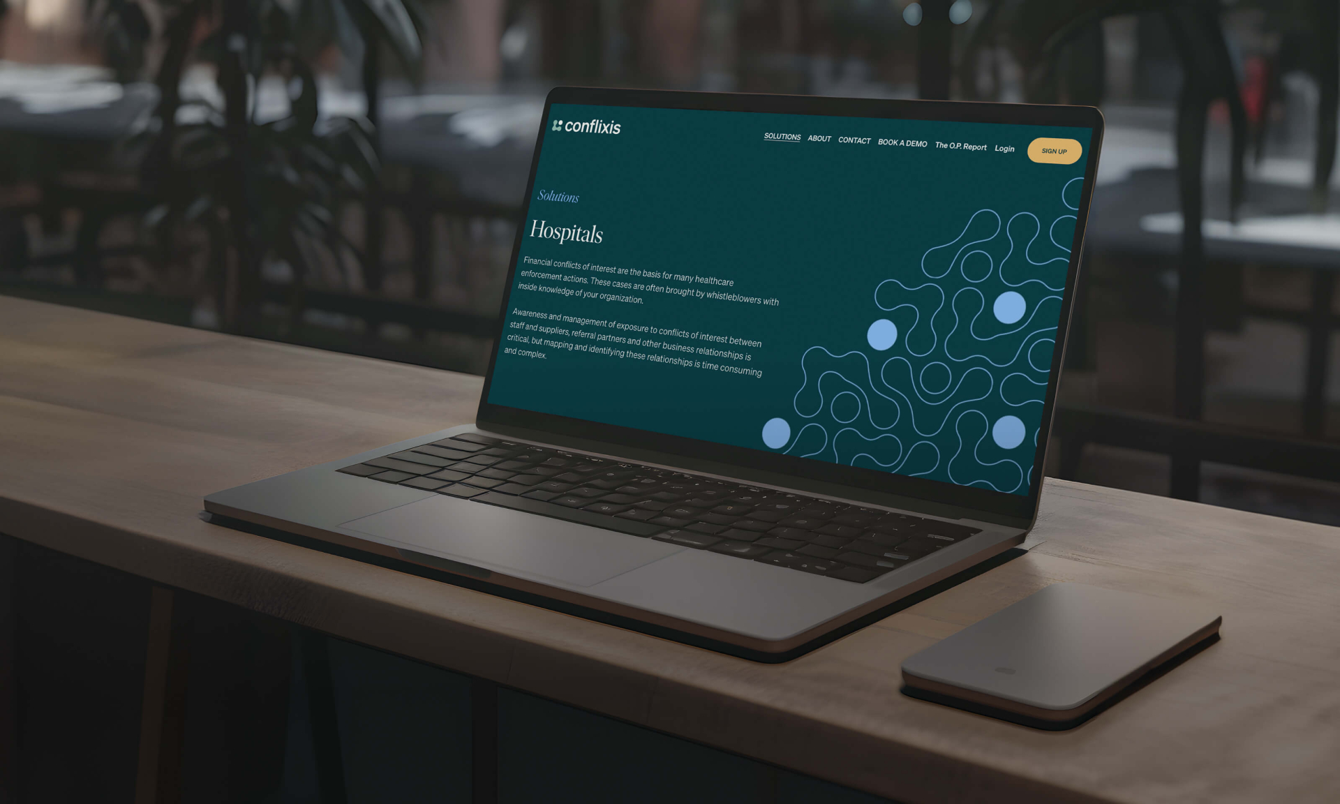 Laptop mit der Darstellung eines Webseitendesigns mit abstrakten blauen Formen auf einem dunkelgrünen Hintergrund.