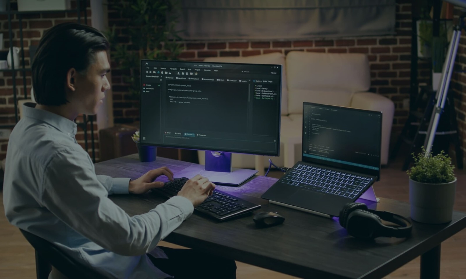 Asiatischer Programmierer, der in seinem Homeoffice an einem Desktop-Computer und einem Laptop programmiert. Softwareentwicklung.