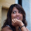 A portrait of a pensive woman with dark hair, resting her chin on her hand and gazing to the side.