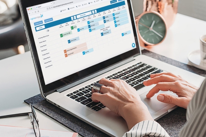 Hände tippen auf einem Laptop, der eine Projektmanagementsoftware mit Gantt-Diagramm zur Terminplanung anzeigt.