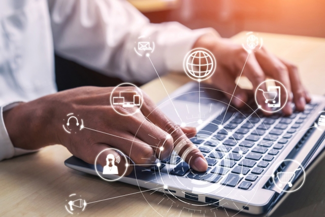 Hands typing on laptop with digital marketing icons overlay for online business.