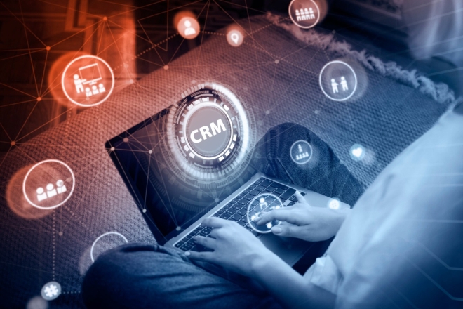 Person using laptop with CRM software interface overlay for customer relationship management.