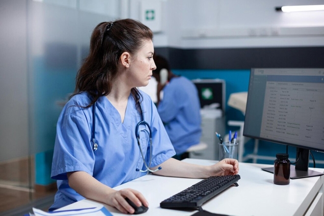 Krankenschwester in Arbeitskleidung bei der Arbeit an einem Computer in einem modernen Krankenhausbüro. Fachkraft im Gesundheitswesen.