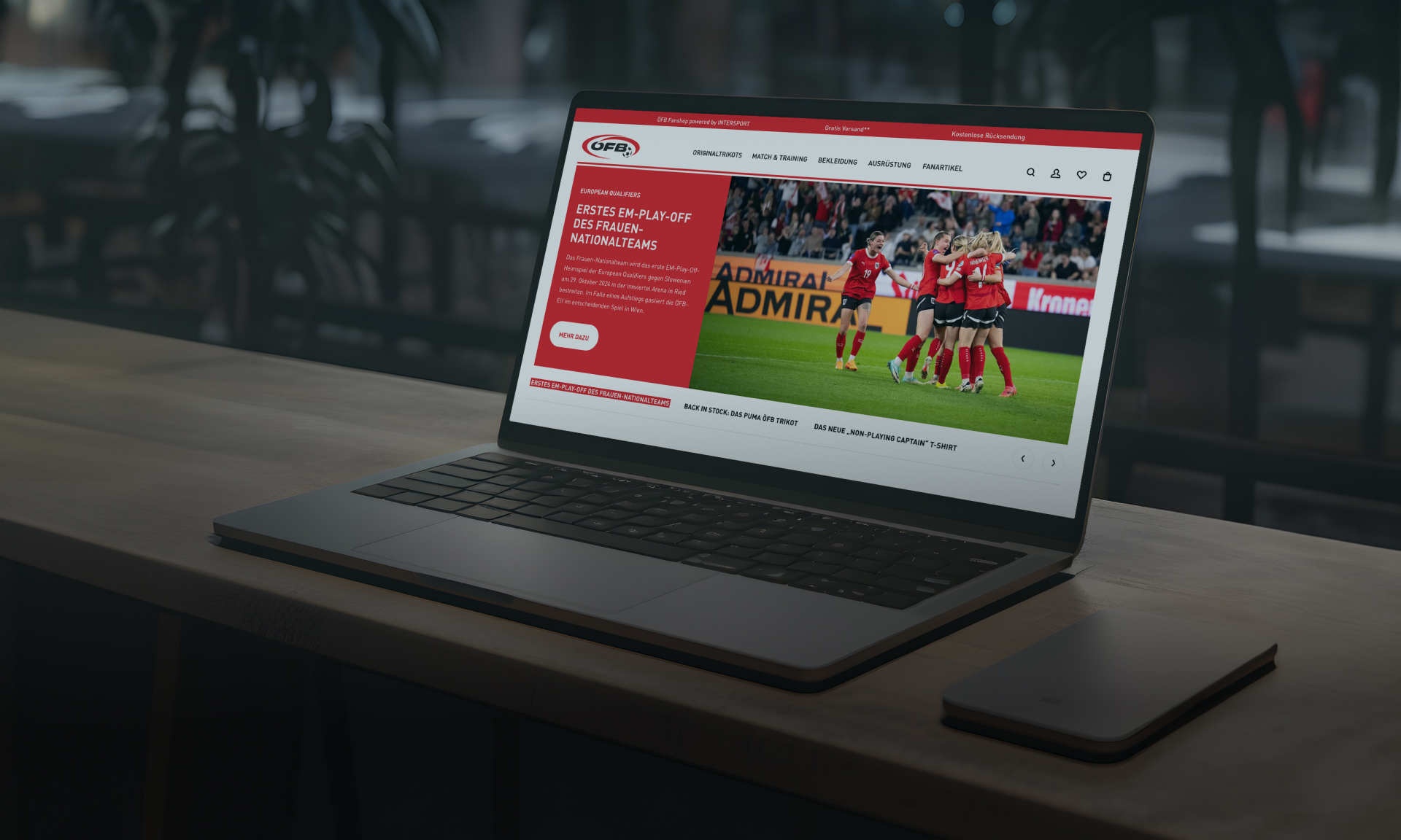 Laptop displaying the Admira Wacker football club website on a wooden surface.