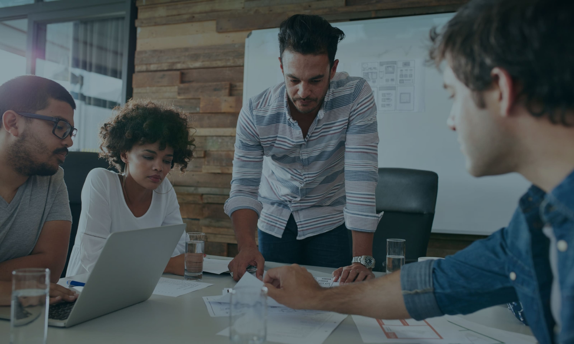 A diverse team collaborating on business strategy in a modern office meeting room.