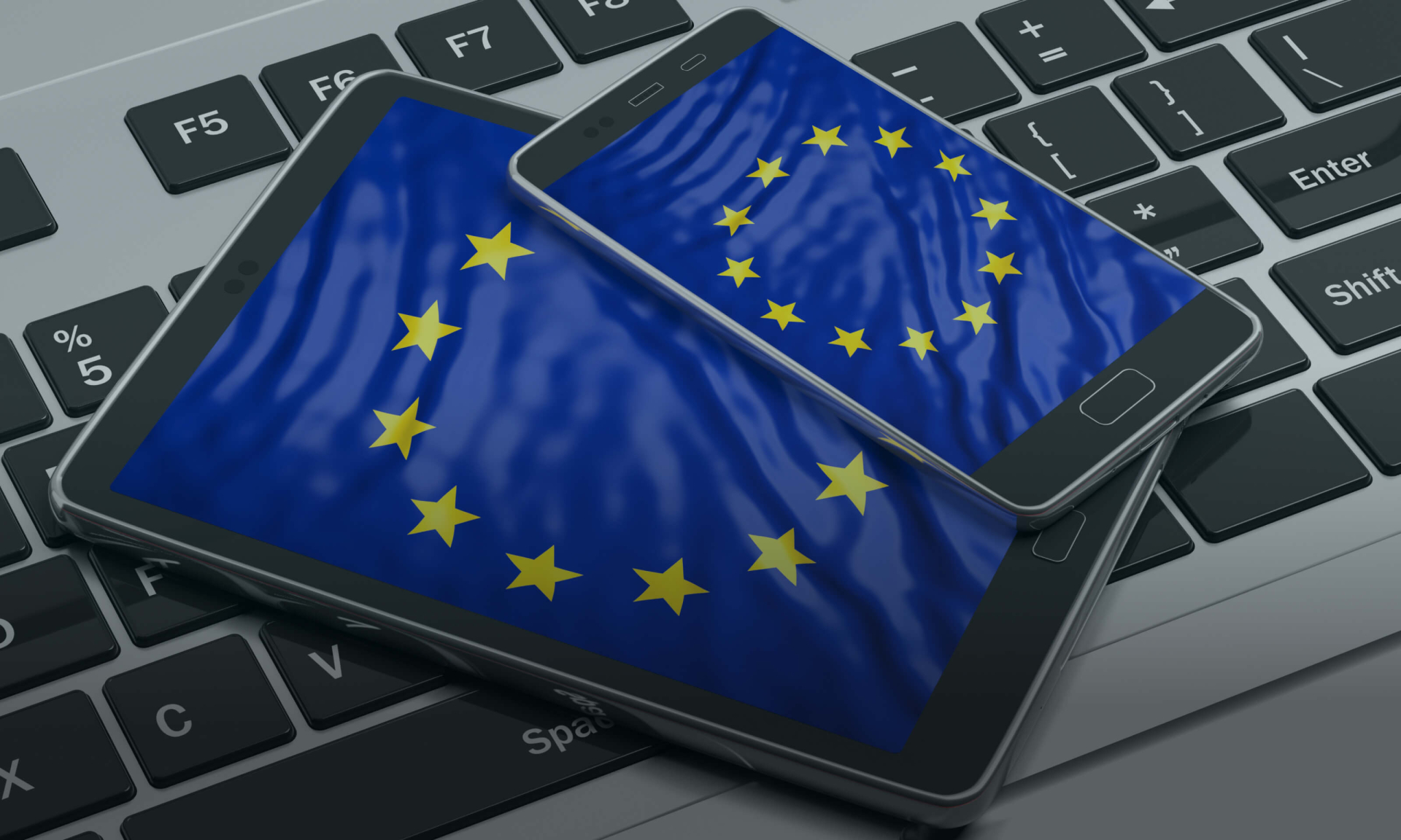 Eine auf Tablet- und Smartphone-Bildschirmen dargestellte Flagge der Europäischen Union, platziert auf einer Laptop-Tastatur.