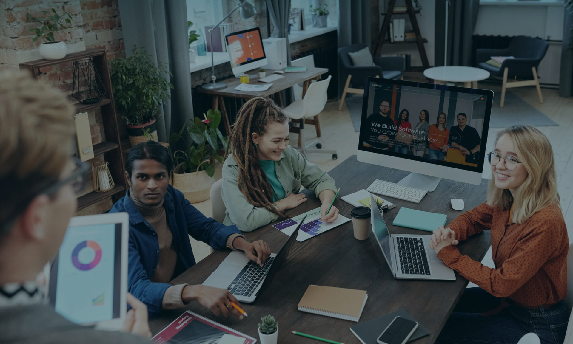 A diverse team is collaborating in a modern office, video conferencing with remote colleagues.