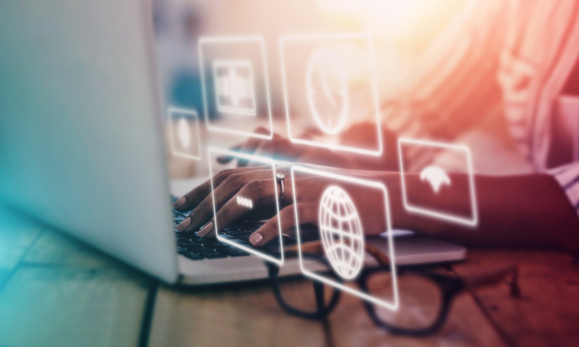 Hands typing on laptop with glowing digital icons, symbolizing online business and global connectivity.