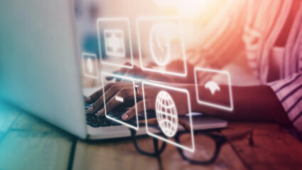Hände, die auf einem Laptop tippen, mit leuchtenden digitalen Icons, die Online-Geschäft und globale Vernetzung symbolisieren.