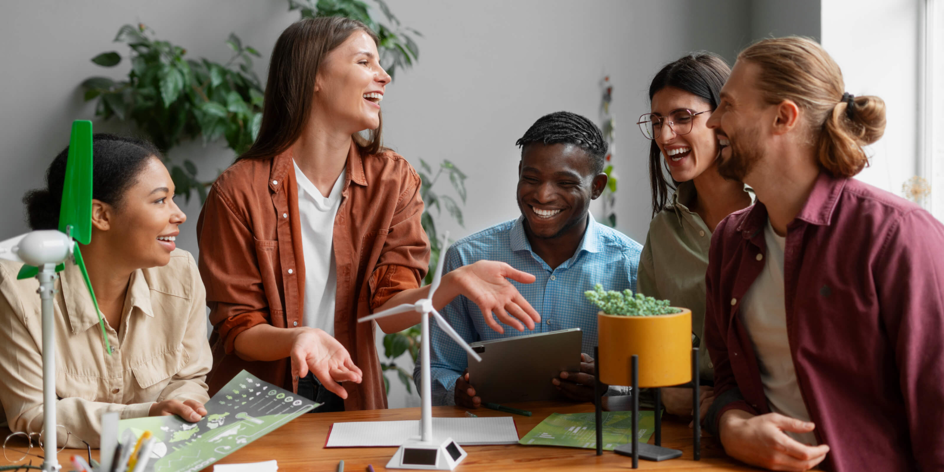 Ein diverses Team erarbeitet in einem Brainstorming nachhaltige Energielösungen mit Windturbinenmodellen im Büro.